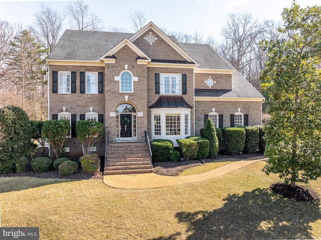 colonial house with a front yard, brick siding, and roof with shingles