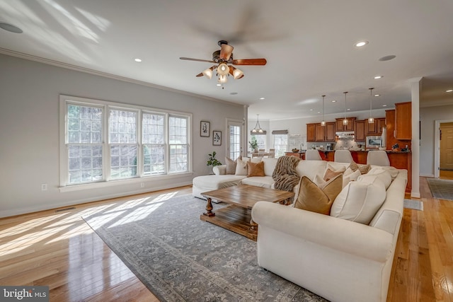 living room featuring ceiling fan, light wood-style flooring, recessed lighting, baseboards, and crown molding