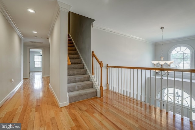 hallway featuring a chandelier, recessed lighting, baseboards, ornamental molding, and light wood finished floors