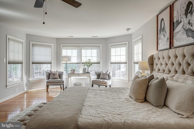 bedroom with visible vents, wood finished floors, a ceiling fan, and baseboards