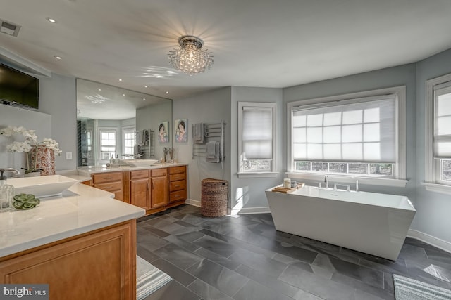 bathroom with a freestanding bath, visible vents, two vanities, and a sink