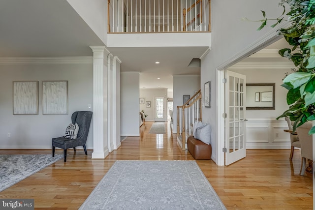 foyer entrance featuring ornamental molding, decorative columns, stairway, and wood finished floors