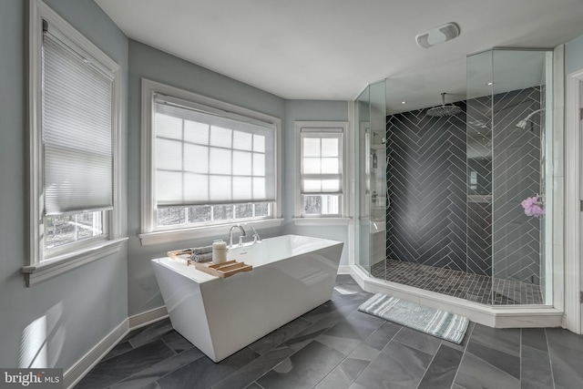 bathroom with a stall shower, a freestanding tub, and baseboards