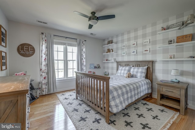 bedroom featuring wallpapered walls, light wood-style flooring, visible vents, and baseboards