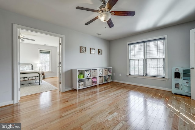 recreation room featuring a ceiling fan, visible vents, baseboards, and wood finished floors