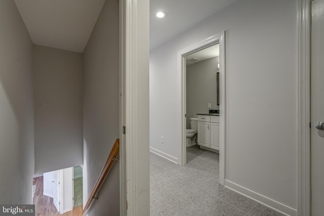 hallway featuring visible vents, baseboards, and an upstairs landing