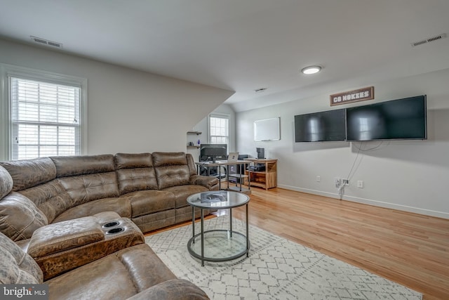 living area with visible vents, vaulted ceiling, baseboards, and wood finished floors