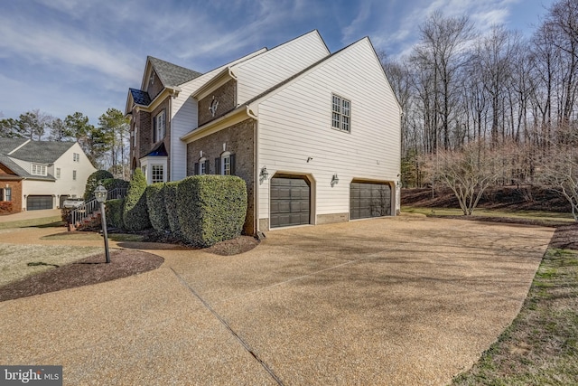 view of side of property featuring a garage, concrete driveway, and brick siding