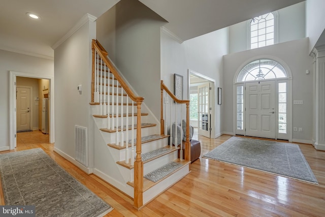 foyer with ornamental molding, visible vents, baseboards, and wood finished floors