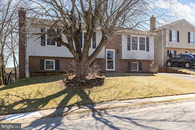 bi-level home with a chimney, a front lawn, and brick siding