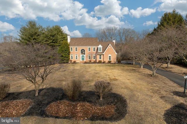 view of front of house featuring a chimney and a front yard