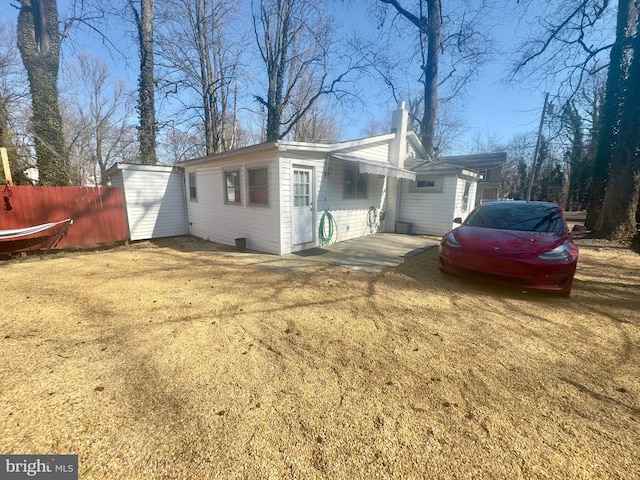 view of side of property with a chimney and fence