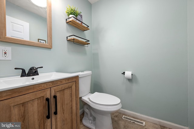 bathroom with toilet, vanity, baseboards, visible vents, and tile patterned floors