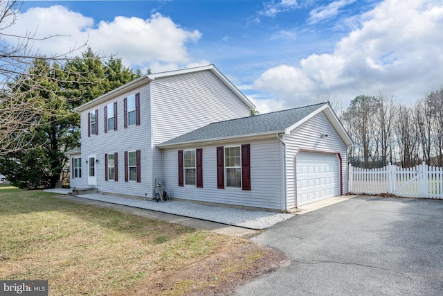 view of side of property with roof with shingles, a lawn, an attached garage, and fence