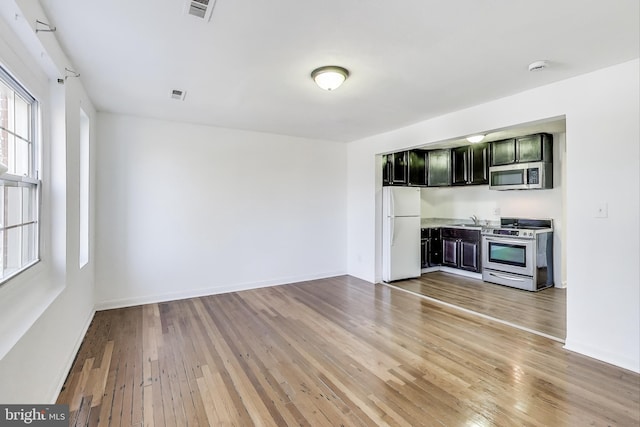 unfurnished living room with baseboards, visible vents, and light wood finished floors