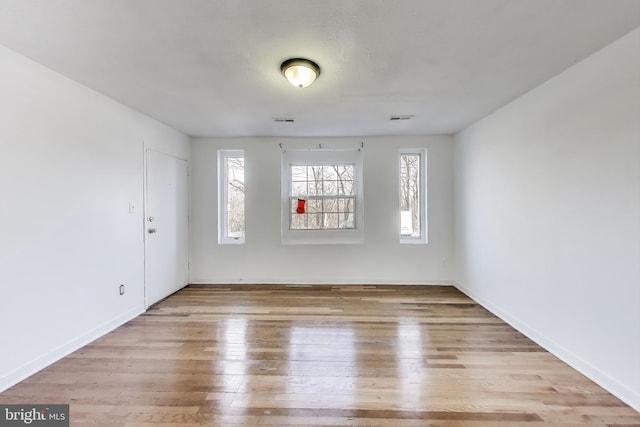 unfurnished room featuring baseboards, visible vents, and wood finished floors