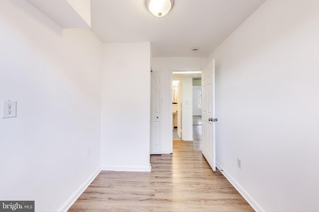 hall with light wood-style flooring and baseboards