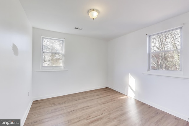 empty room featuring baseboards, visible vents, and wood finished floors