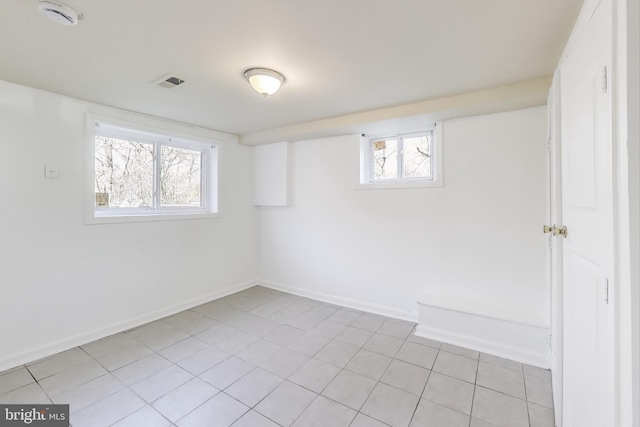 empty room featuring plenty of natural light, visible vents, and baseboards