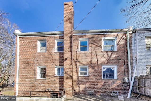 exterior space with brick siding, fence, and a chimney