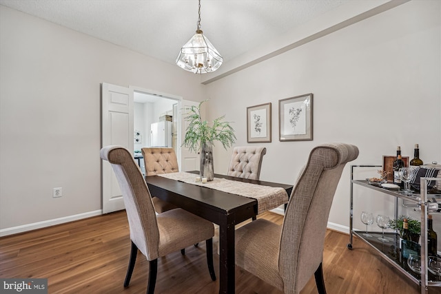 dining area featuring a notable chandelier, baseboards, and wood finished floors