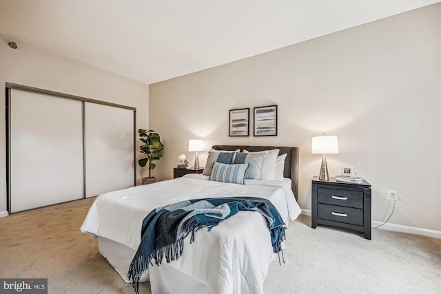 bedroom featuring baseboards, a closet, and light colored carpet