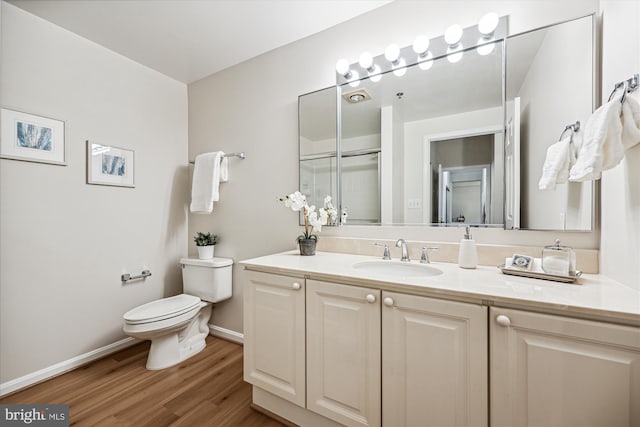 bathroom with vanity, wood finished floors, toilet, and baseboards