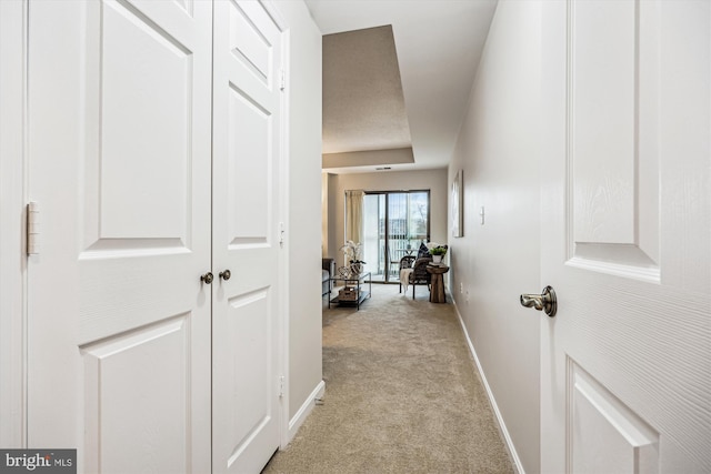 corridor featuring light carpet and baseboards