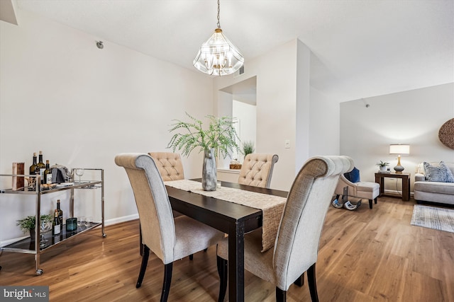 dining area with light wood-type flooring, baseboards, and a chandelier