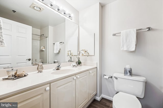 bathroom featuring baseboards, toilet, wood finished floors, walk in shower, and vanity