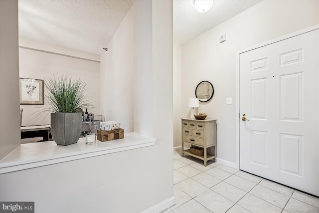 foyer featuring a textured ceiling, baseboards, and tile patterned floors