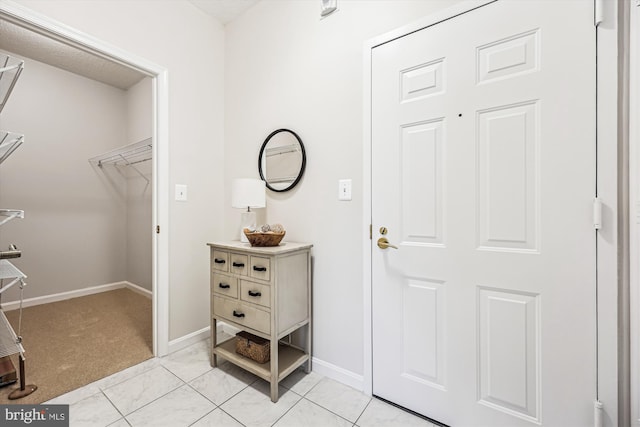 foyer entrance featuring light tile patterned floors, light carpet, and baseboards