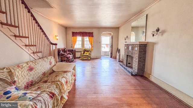 living area featuring a fireplace, stairway, ornamental molding, wood finished floors, and baseboards