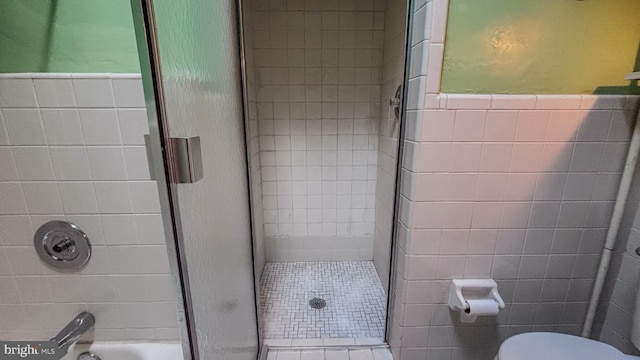 bathroom with toilet, wainscoting, and tile walls