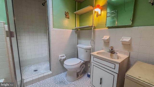 full bath with a stall shower, toilet, a wainscoted wall, tile patterned flooring, and vanity