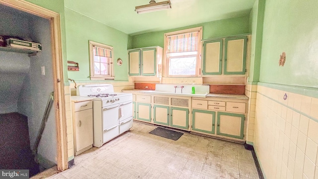 kitchen featuring a wainscoted wall, double oven range, plenty of natural light, and light floors