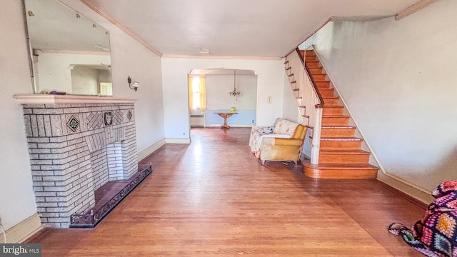 corridor featuring arched walkways, stairway, ornamental molding, wood finished floors, and baseboards