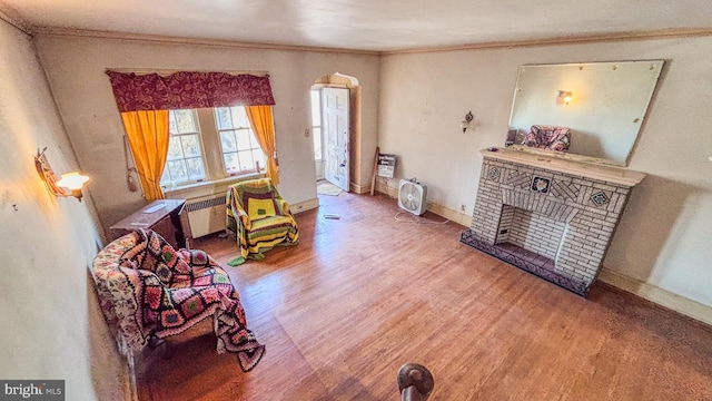 living area featuring ornamental molding, a fireplace, baseboards, and wood finished floors