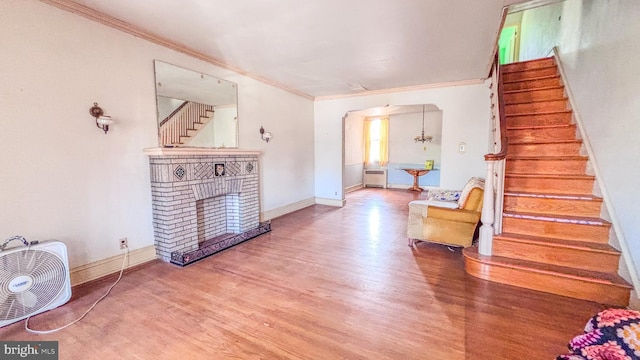 interior space with a fireplace, wood finished floors, baseboards, stairs, and ornamental molding