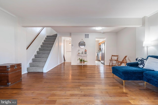 sitting room featuring baseboards, visible vents, stairway, and wood finished floors