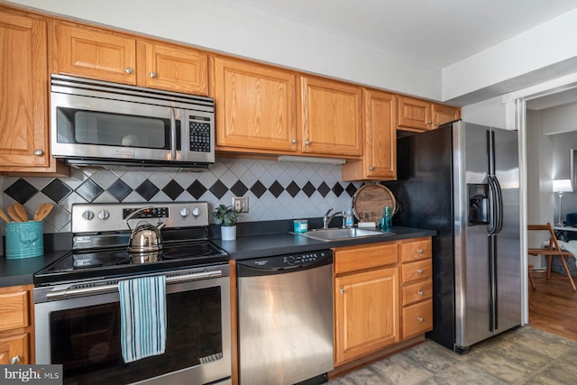 kitchen featuring dark countertops, appliances with stainless steel finishes, decorative backsplash, and a sink