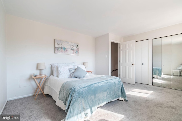 carpeted bedroom featuring baseboards and multiple closets