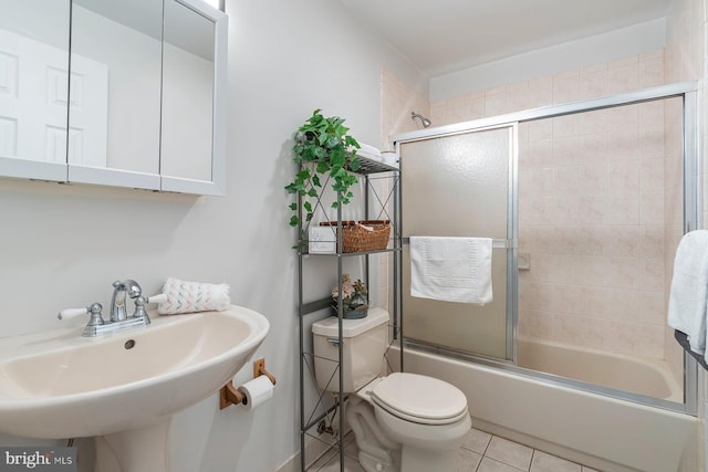 full bathroom featuring toilet, shower / bath combination with glass door, tile patterned flooring, and a sink