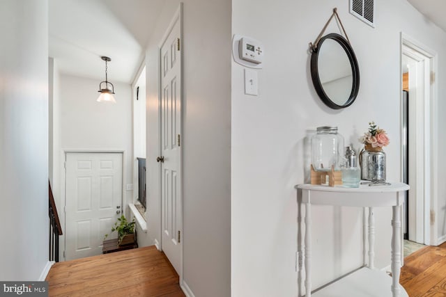 corridor featuring baseboards, visible vents, and light wood-style floors