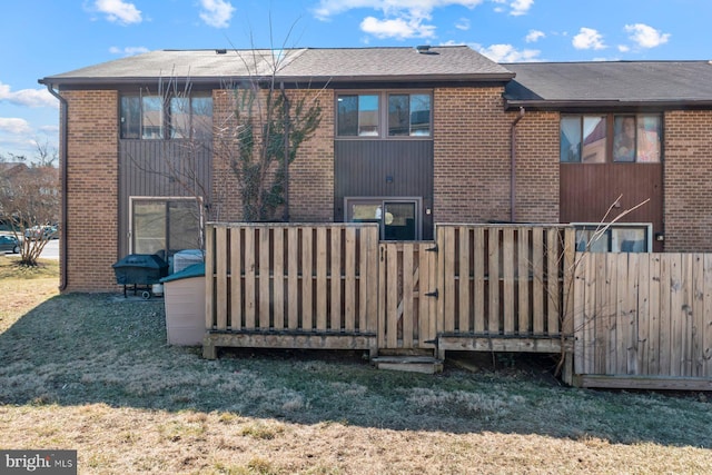 back of house featuring a yard, a gate, fence, and brick siding