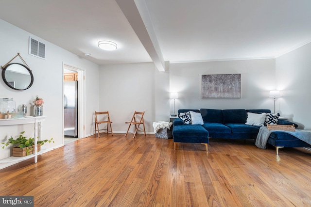 living room with beam ceiling, visible vents, baseboards, and hardwood / wood-style flooring