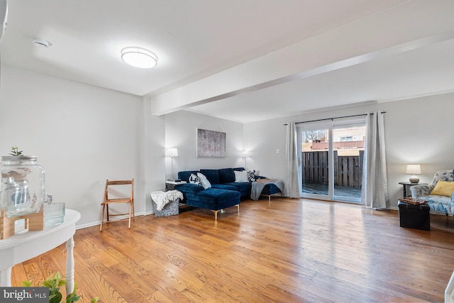 sitting room featuring beam ceiling, baseboards, and wood finished floors