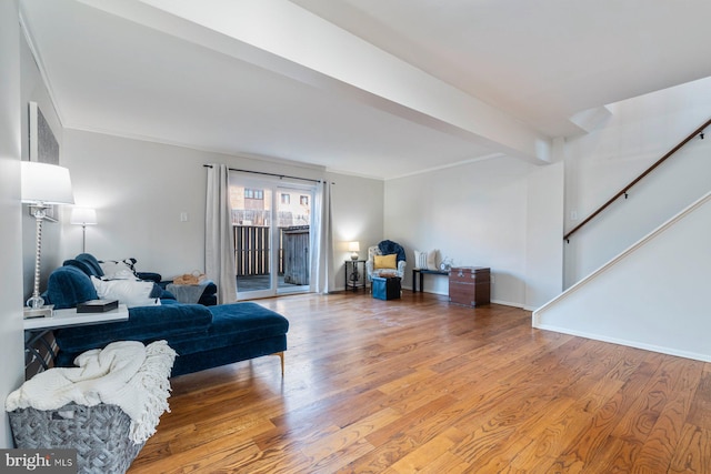 living area with ornamental molding, stairway, wood finished floors, and beam ceiling