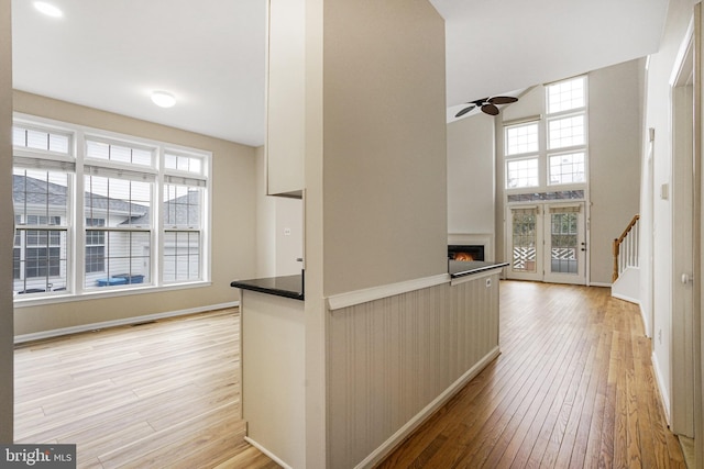 hall featuring stairway, baseboards, a towering ceiling, and light wood finished floors