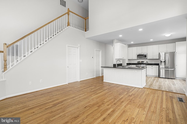 kitchen featuring stainless steel appliances, dark countertops, a sink, and visible vents